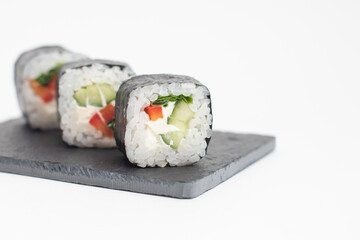 Rolls with vegetables are served on a black slate board