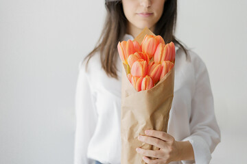 woman holding with her left hand a bouquet of orange tulips