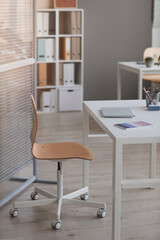 Image of empty table with laptop on it and chair at modern office