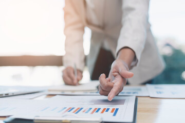 Business women are analyzing and evaluating marketing for a company using graphs on their desks in the office Concept of business risk analysis and assessment