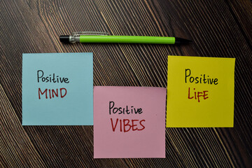 Positive Mind, Positive Vibes, Positive Life write on sticky note isolated on Wooden Table.