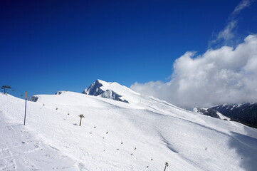 Obraz premium Winter landscape in the mountains. Snow-capped mountain peaks, blue sky, ski slopes.
