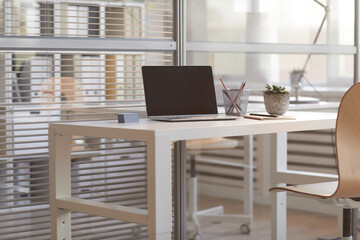 Image of laptop with blank screen on the table at empty office interior