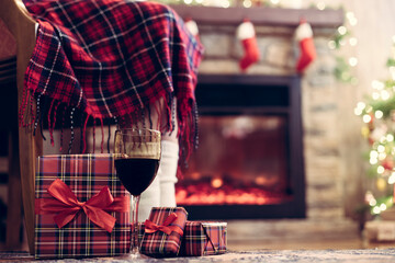 Woman legs in a socks covered plaid sitting and relaxation on armchair near fareplace and christmas...