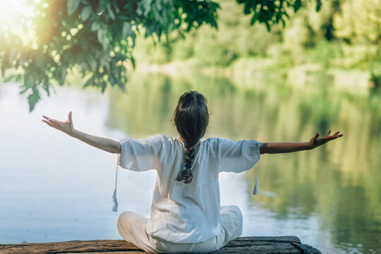 a woman in a white robe is sitting on a rock in the water - Self-Discovery Meditation in Nature by T