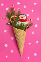 Snowman, Christmas tree twigs and lollipop in a waffle cone. Red background with snowflakes. An original sweet gift.