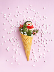 Snowman, marshmallows, Christmas tree twigs and lollipops in a waffle cone. Pink background. An original sweet gift.