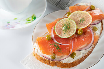sandwich with salmon slices, fresh herbs, lemon and lime slices