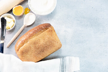 a loaf of wheat bread with baking ingredients on grey backgraund
