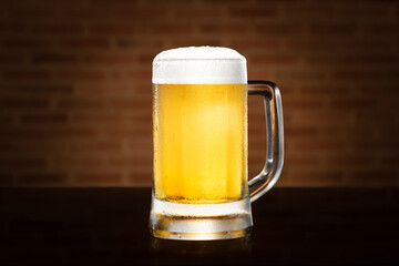 Beer. Glass of cold golden beer have froth in glass with water drops brown brick wall background, Closeup beer foam in glasses on black table with copy space, Drink celebration party holiday concept.