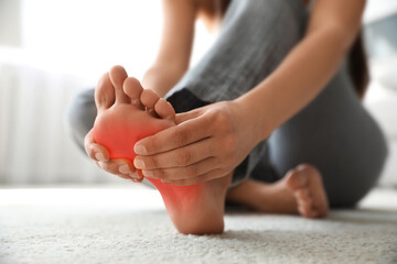 Woman suffering from foot pain at home, closeup