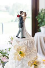 Detail of a pretty just married couple figure on the top of a beautiful wedding cream cake...