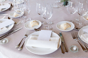 Detail of a beautiful wedding table with crockery, cutlery and wine glasses with a blank menu paper for mock up