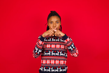 Young beautiful African American woman standing against red background Has rejection angry...