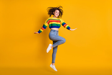 Fototapeta na wymiar Full length photo of jumping lady wearing casual colorful sweater dancing pointing standing one leg isolated yellow color background