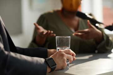 Close-up of man sitting at the table with glass of water during business interview with woman