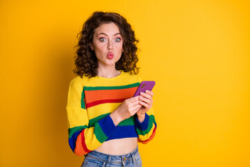 Photo of charming pretty brunette hair young lady blow kiss hold telephone wear pullover isolated on bright yellow background