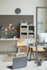 Image of desk with laptop computer on it at modern empty office