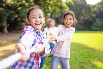 Happy Children playing tug of war at the park