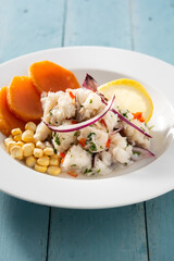 Traditional peruvian ceviche with fish, sweet potato, corn and vegetables on blue wooden table