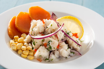 Traditional peruvian ceviche with fish, sweet potato, corn and vegetables on blue wooden table