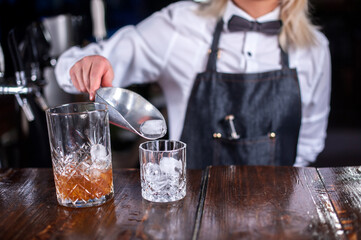 Girl barman makes a cocktail in the beerhouse
