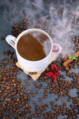 White cup full of coffee beans close up against the dark grey background. Coffee mug. Morning espresso.	