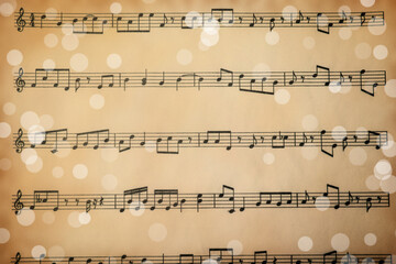 Top view of old sheet with Christmas music notes as background, bokeh effect
