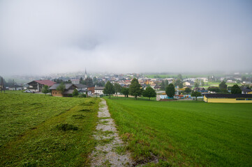Fototapeta na wymiar A countryside road to a foggy alpine village