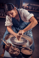 Stylish professional potter sculptor works with clay on a Potter's wheel and at the table with the tools. Hand work.