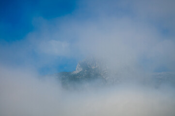 A sunlit mountain top in a disappearing fog