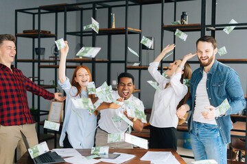 Portrait of cheerful business team of multi-ethnic employees celebrating victory and big profit at office workplace. Cheerful excited young business man and woman throwing away banknote. Rain of money