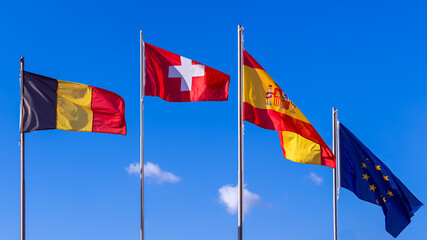 Flag of Belgium, flag of Switzerland, flags of Spain and flag of European Union against the blue sky