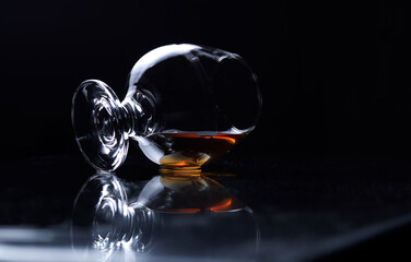 A glass of whisky lies on a dark background. lying cognac glass with cognac or brandy. alcohol drink lie on a checkered surface. night life. 