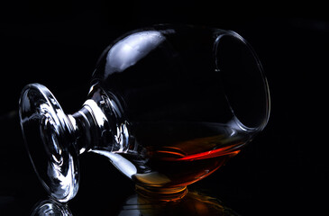 A glass of whisky lies on a dark background. lying cognac glass with cognac or brandy. alcohol...