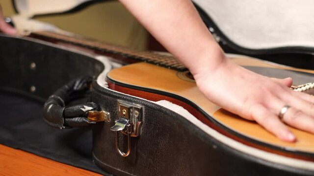 Close up shot of male hands putting guitar in case