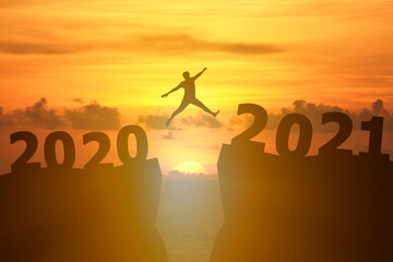 Concept Happy new year 2021 Silhouette image of happy man jump from 2020 up to 2021 on beautiful sky sunrise.