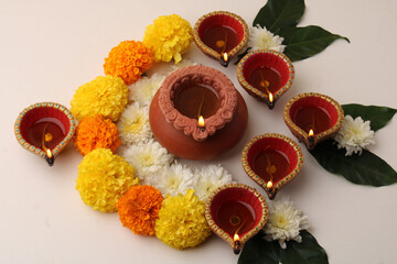 Flower Rangoli for Diwali or Pongal Festival made using Marigold or Zendu flowers and Clay Oil Lamp over white background.