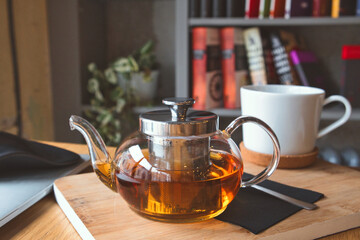 Cozy remote working morning in cafe - cup of hot herbal tea, laptop on desk and books