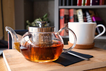 Cozy remote working morning in cafe - cup of hot herbal tea, laptop on desk and books