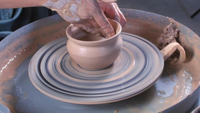 Handicraftsman making ceramic pot on the pottery wheel . Handicraft industry. Close-up.