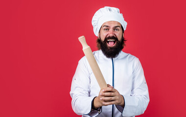 Naklejka premium skilled baker use kitchen utensils for cooking. male chef in hat prepare healthy meal. handsome man with beard and moustache cooking food. professional restaurant cook baking. nice rolling pin