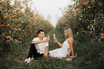 Happy couple on a picnic drinking white wine and smiling at each other on a summer day. 