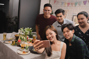 Group of Asian friends taking a selfie while having dinner after work.