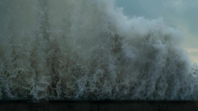 Powerful wave crashing into seawall with huge splashes