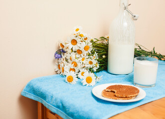 Simply stylish wooden kitchen with bottle of milk and glass on table, summer flowers camomile, healthy foog moring concept