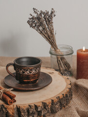 Handmade ceramic craft ware. Rustic napkin and kitchen tools with lavender and candle. Ceramic cup with cinnamon on a wooden stand. Handmade ceramic dishes