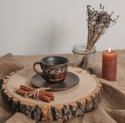 Handmade ceramic craft ware. Rustic napkin and kitchen tools with lavender and candle. Ceramic cup with cinnamon on a wooden stand. Handmade ceramic dishes