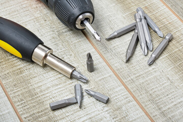 electric screwdriver, self-tapping screws, screwdriver bits, tool box on a wooden background
