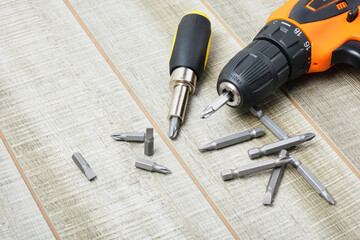 electric screwdriver, self-tapping screws, screwdriver bits, tool box on a wooden background - obrazy, fototapety, plakaty